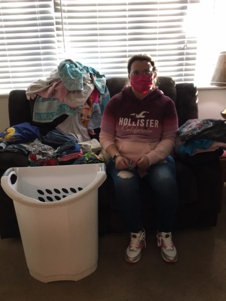 Picture of female supported living services participant sitting on the couch in her own apartment folding her laundry.